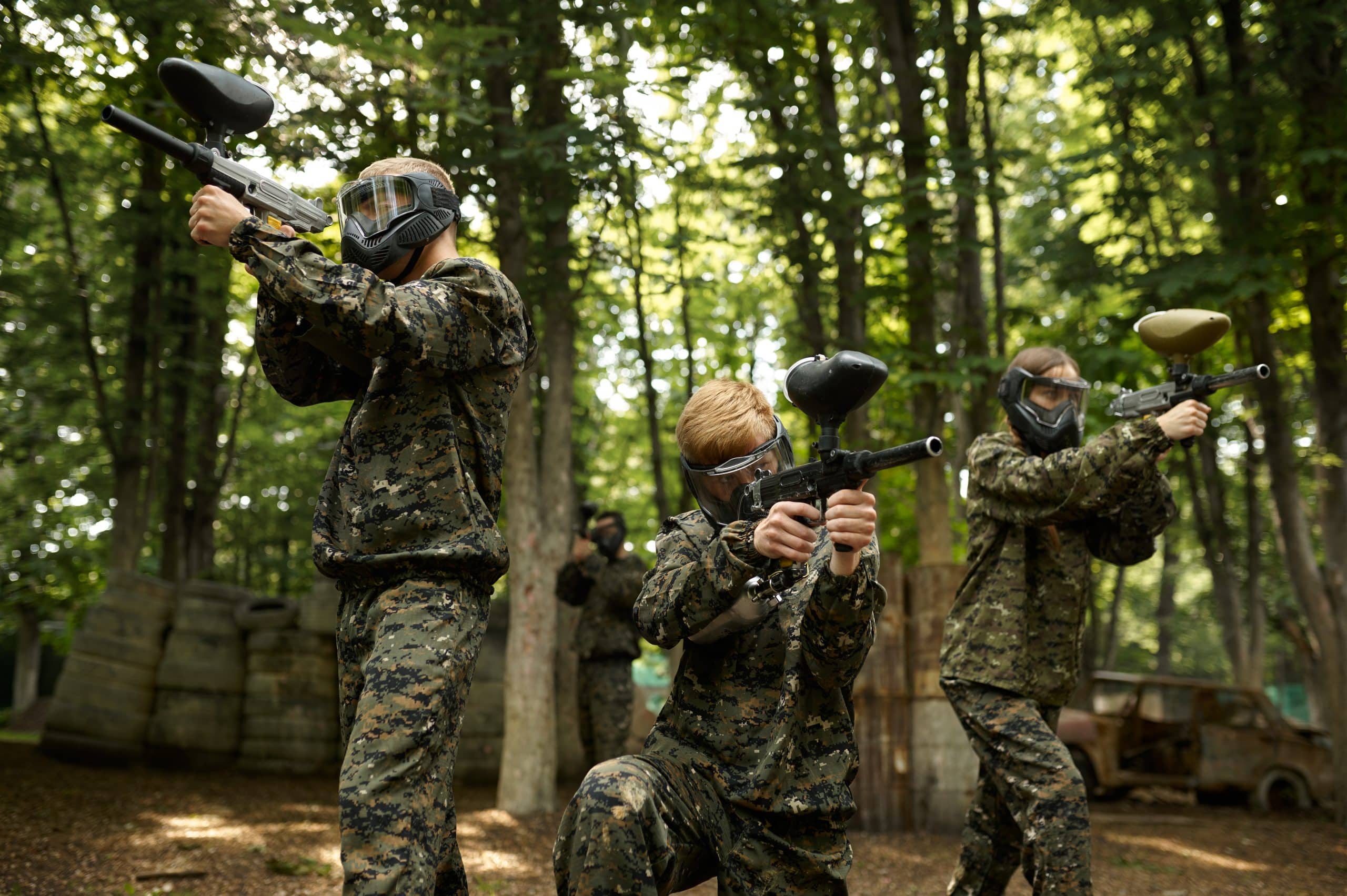 Soldiers in camouflage and masks playing paintball in forest. Extreme sport with pneumatic weapon and paint bullets or markers, military team game outdoors, combat tactics